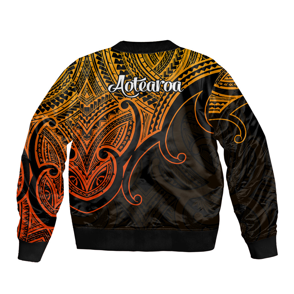 Polynesian bomber jacket back view in gold with black and orange tribal art, Aotearoa text