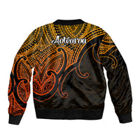 Polynesian bomber jacket back view in gold with black and orange tribal art, Aotearoa text