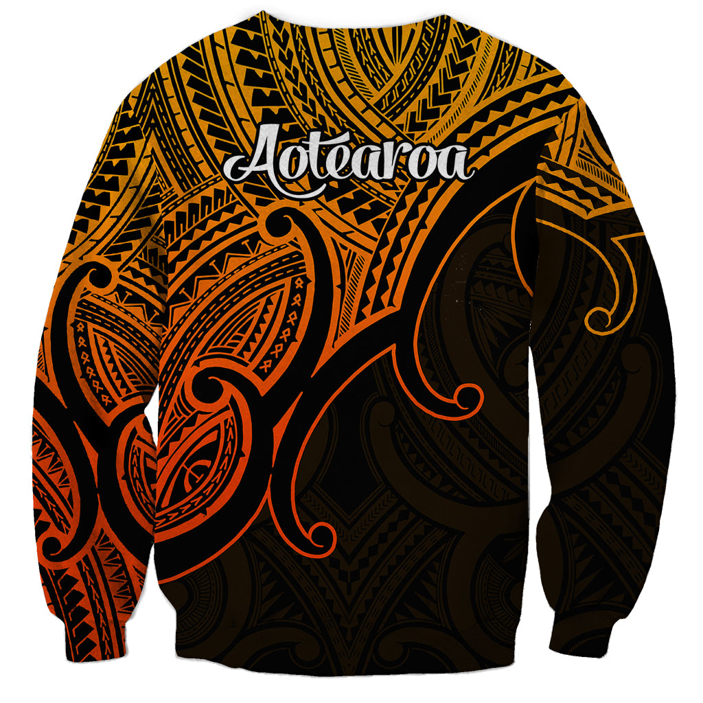 Gold unisex sweatshirt with back tribal print and 'Aotearoa' text, black and red