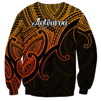 Gold unisex sweatshirt with back tribal print and 'Aotearoa' text, black and red