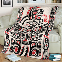 Haida-style throw blanket draped on couch, red/black/white pattern with 'YOUR TEXT'