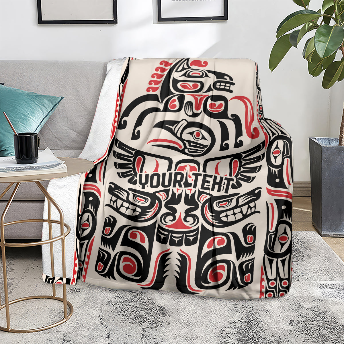 Haida-style throw blanket on gray sofa with red/black/white pattern and 'YOUR TEXT'