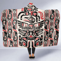 Hooded blanket with large Haida-style graphic pattern in red, black, and white