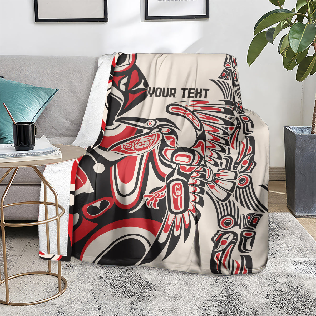 Personalized throw blanket draped on sofa, red/black/white bold abstract design with 'YOUR TEXT'