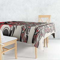 Red and black tablecloth with white abstract tribal pattern, draped on a small table.