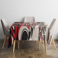 Square tablecloth in red, black, and white tribal pattern on table with four chairs.
