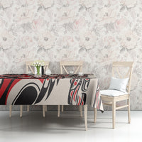 Red-and-black tablecloth with white abstract tribal motifs on a dining table surface.