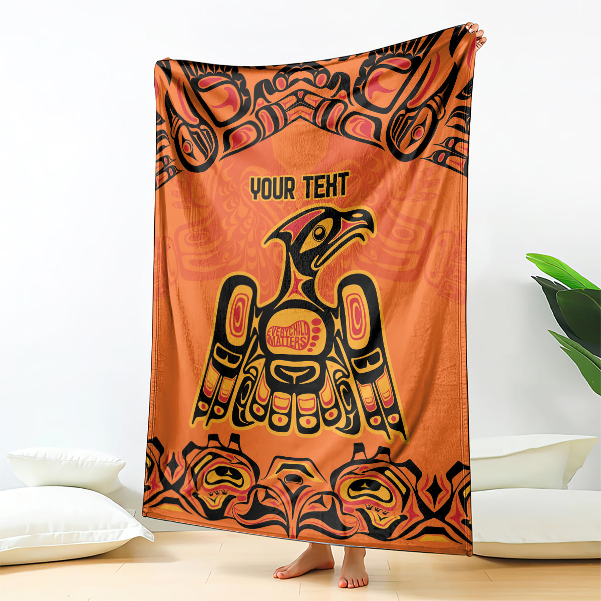 Orange patterned throw blanket with 'YOUR TEXT' and Haida bird and totem illustration