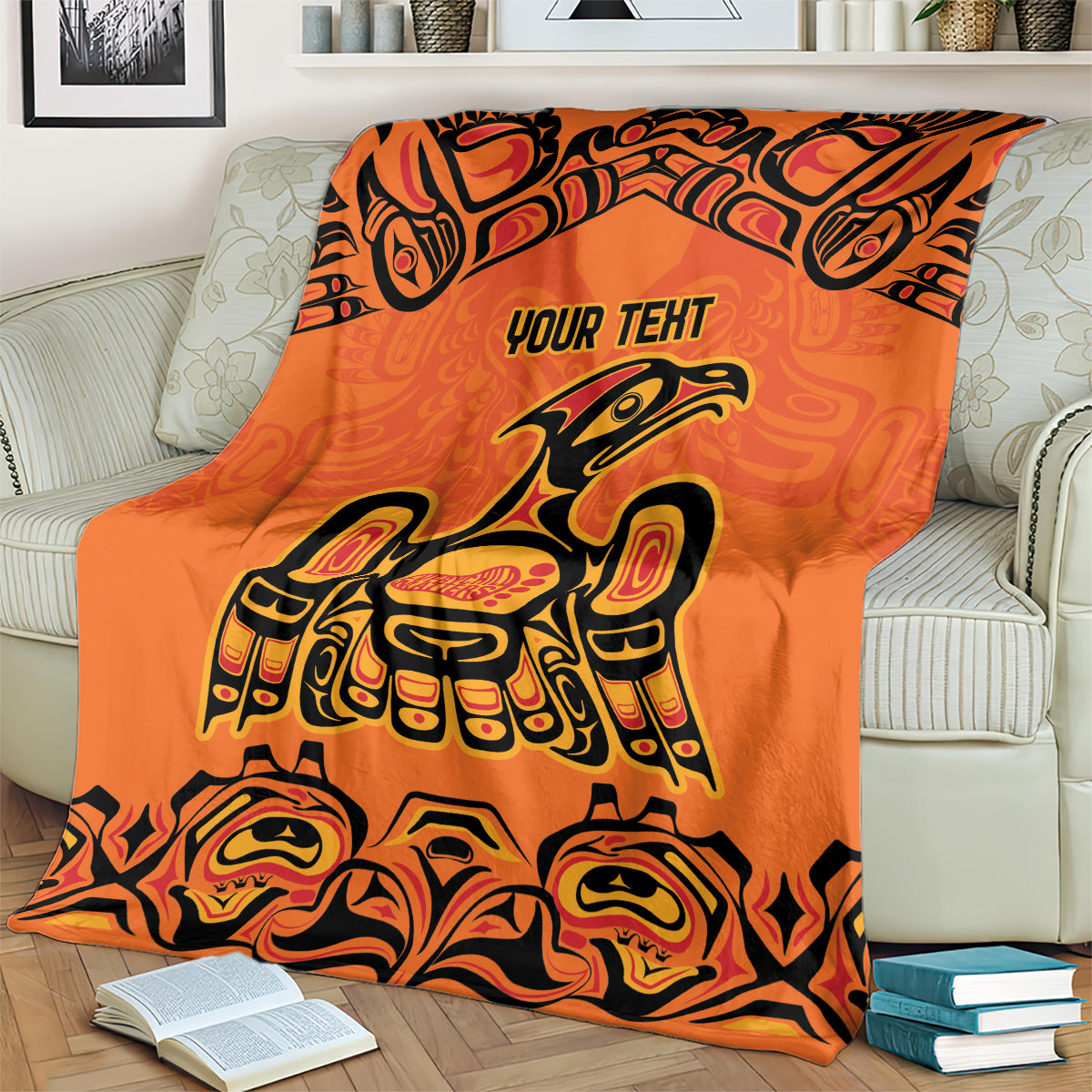 Orange throw blanket with 'YOUR TEXT' and Haida bird and face motifs around edges