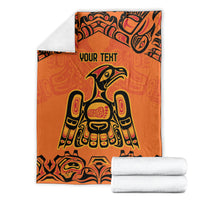 Orange patterned throw blanket with 'YOUR TEXT' and Haida bird graphic, neatly folded