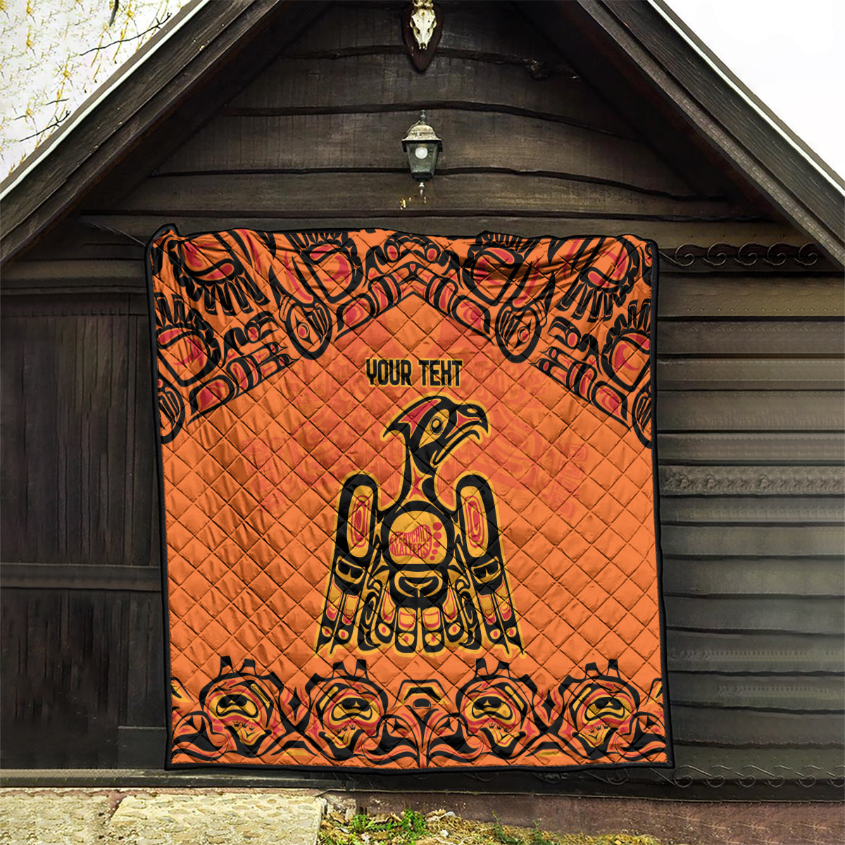 Orange quilt blanket with black border, Haida-style raven centerpiece and "YOUR TENT" text