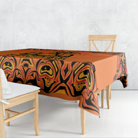 Orange tablecloth with black swirl tribal pattern, draped over dining table