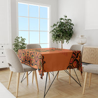 Orange tablecloth with black tribal motif, on dining table with four chairs