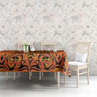 Orange tablecloth with black tribal swirl pattern, dining table with white chairs