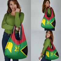 Reusable grocery bag carried by woman, green red yellow and black tent graphic