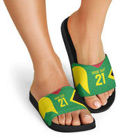 Custom green slide sandals with black sole on feet, star graphic strap with red-yellow accents