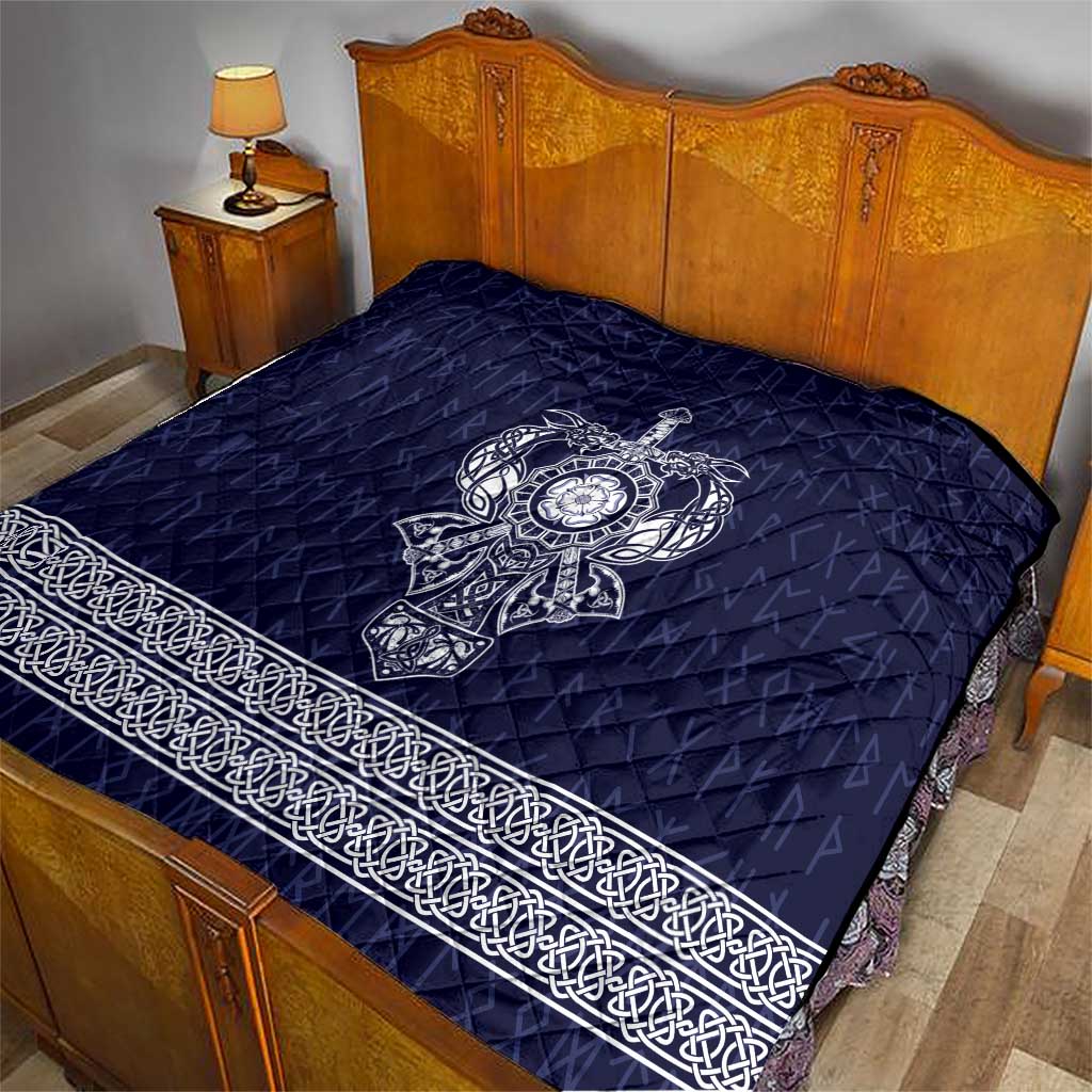 Blue quilted bedspread with white Viking axe emblem and ornate border along edge
