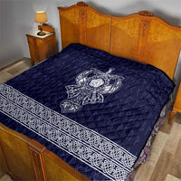 Blue quilted bedspread with white Viking axe emblem and ornate border along edge