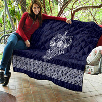 Blue quilt laid over couch with central white Viking axe emblem and decorative border