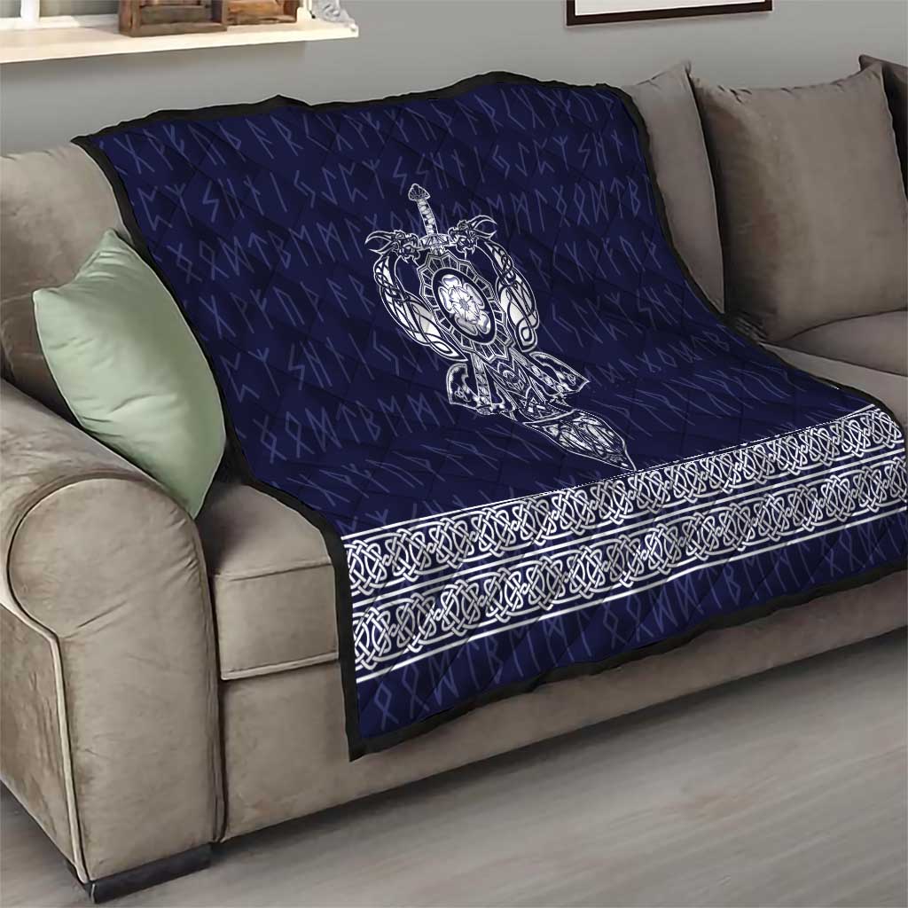 Blue quilt draped over sofa with white Viking axe emblem and ornate border strip