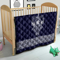 Blue quilt on crib with central white Viking axe emblem and decorative white border