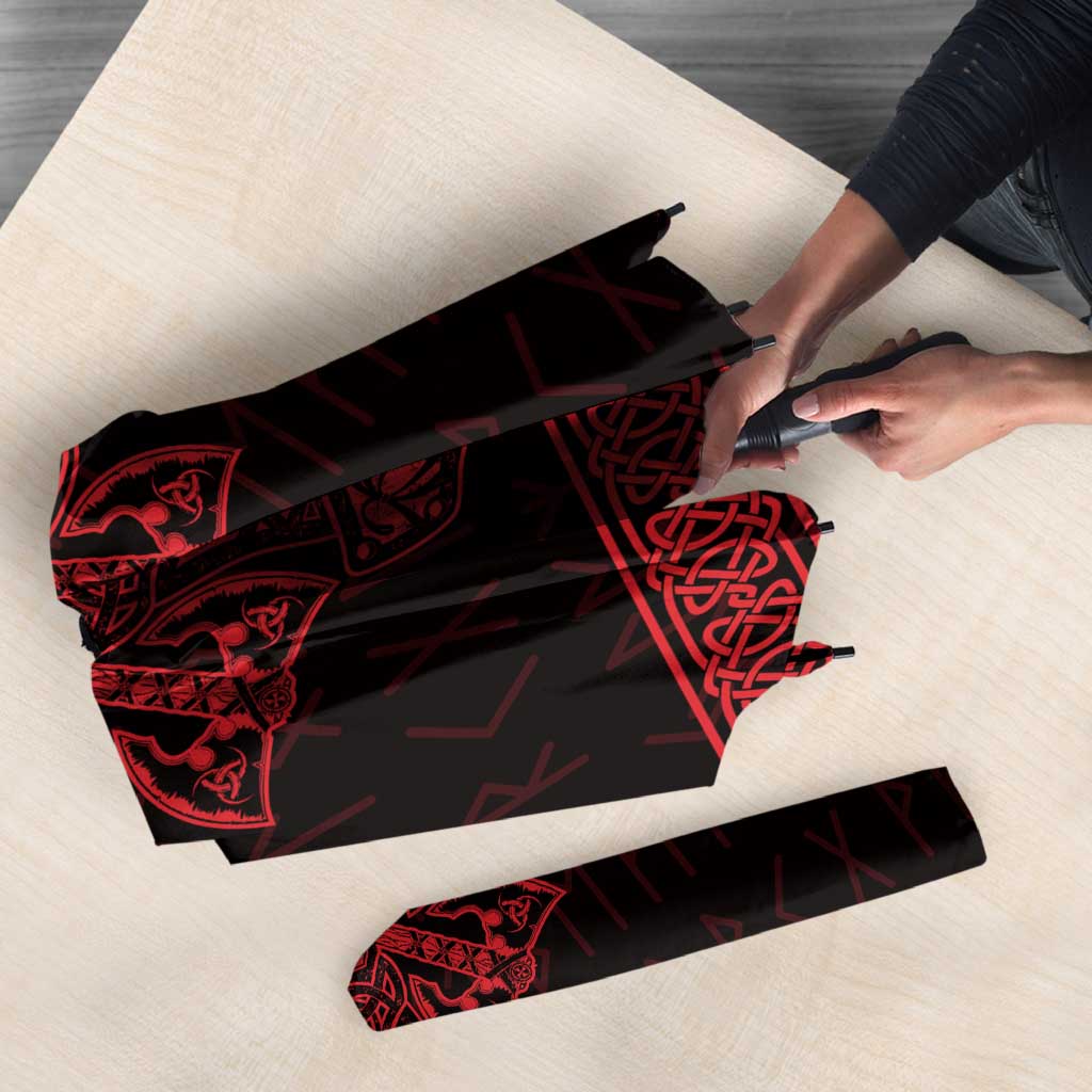 Folded red-and-black Viking-style umbrella with rune graphics, on a surface