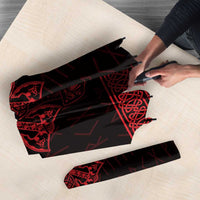 Folded red-and-black Viking-style umbrella with rune graphics, on a surface