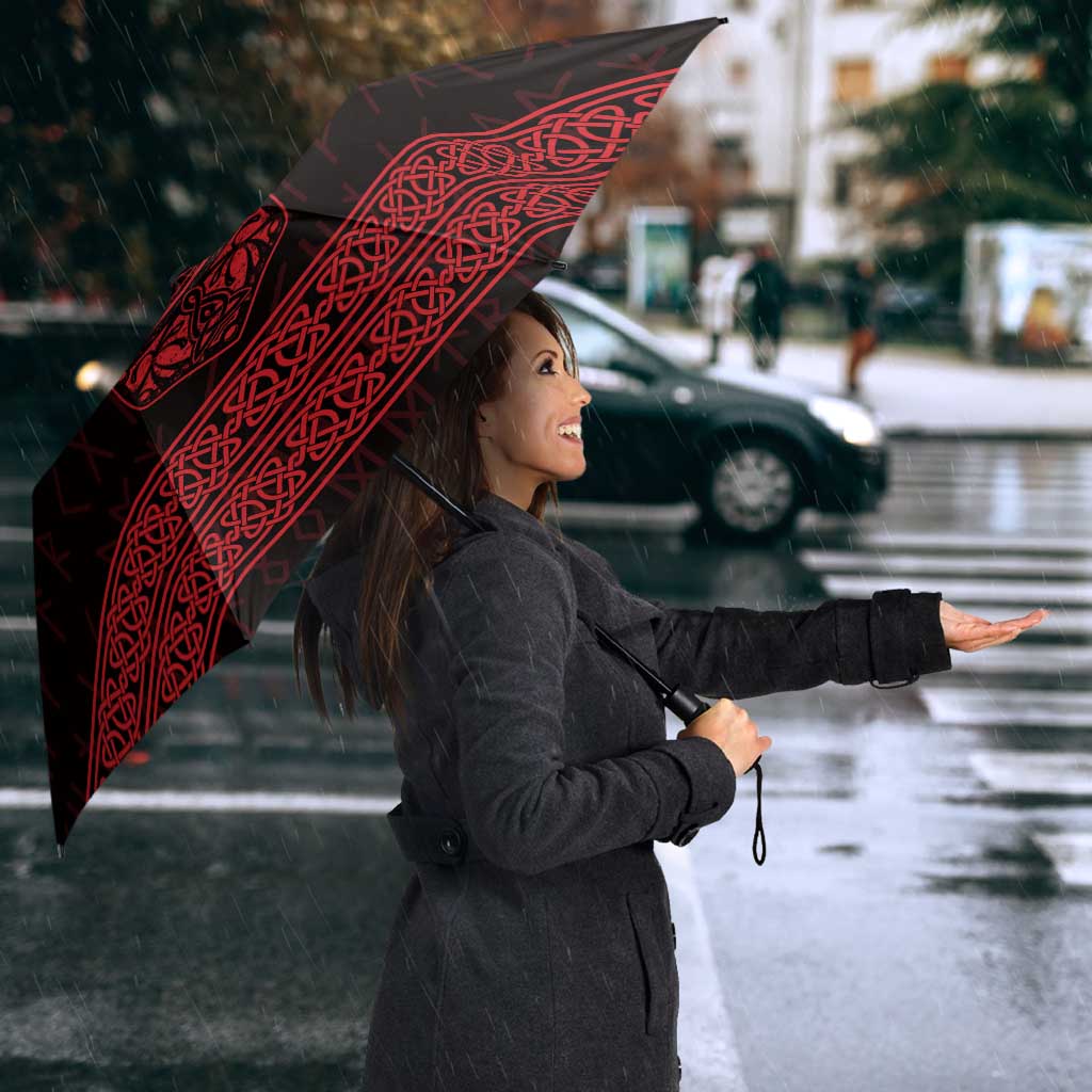 Red-and-black Viking-style umbrella with large rune knot band, held overhead