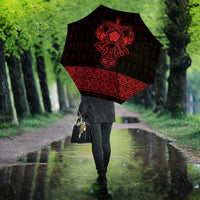 Red-and-black Viking-style umbrella with rune knot print, held open while walking