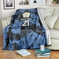 Personalized fleece blanket in blue and navy, flower emblem, 'YOUR TEXT' and 21, draped on couch