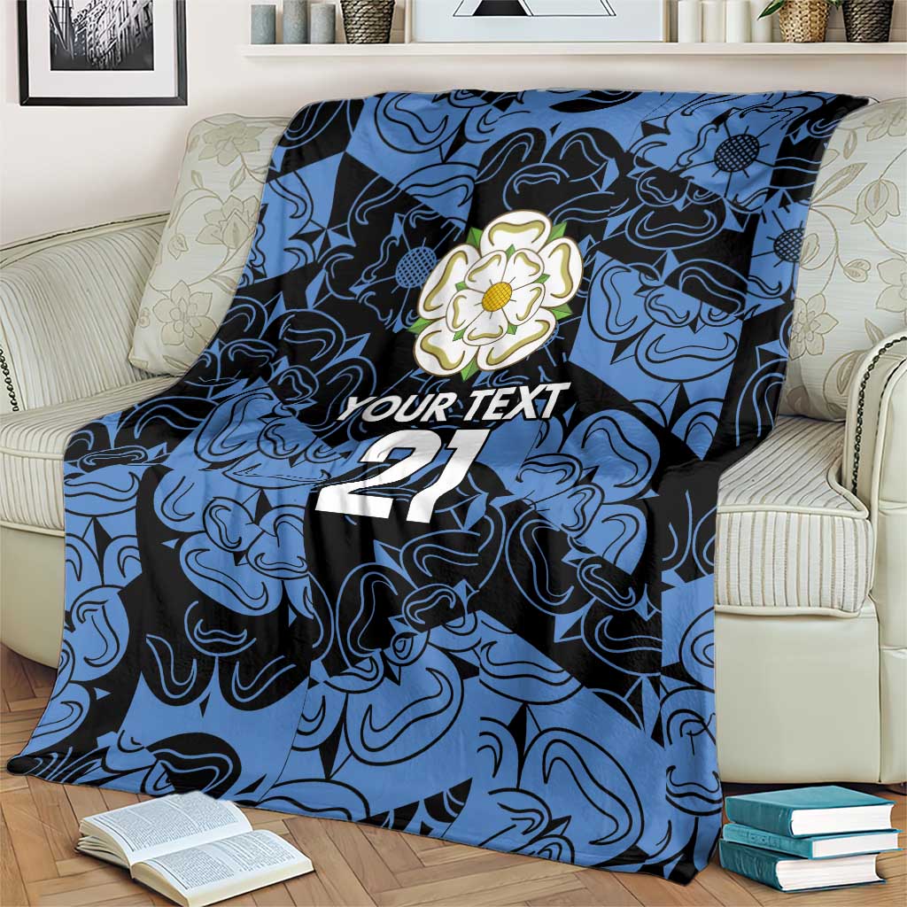 Personalized fleece blanket in blue and navy with flower emblem, 'YOUR TEXT' and 21, draped over chair