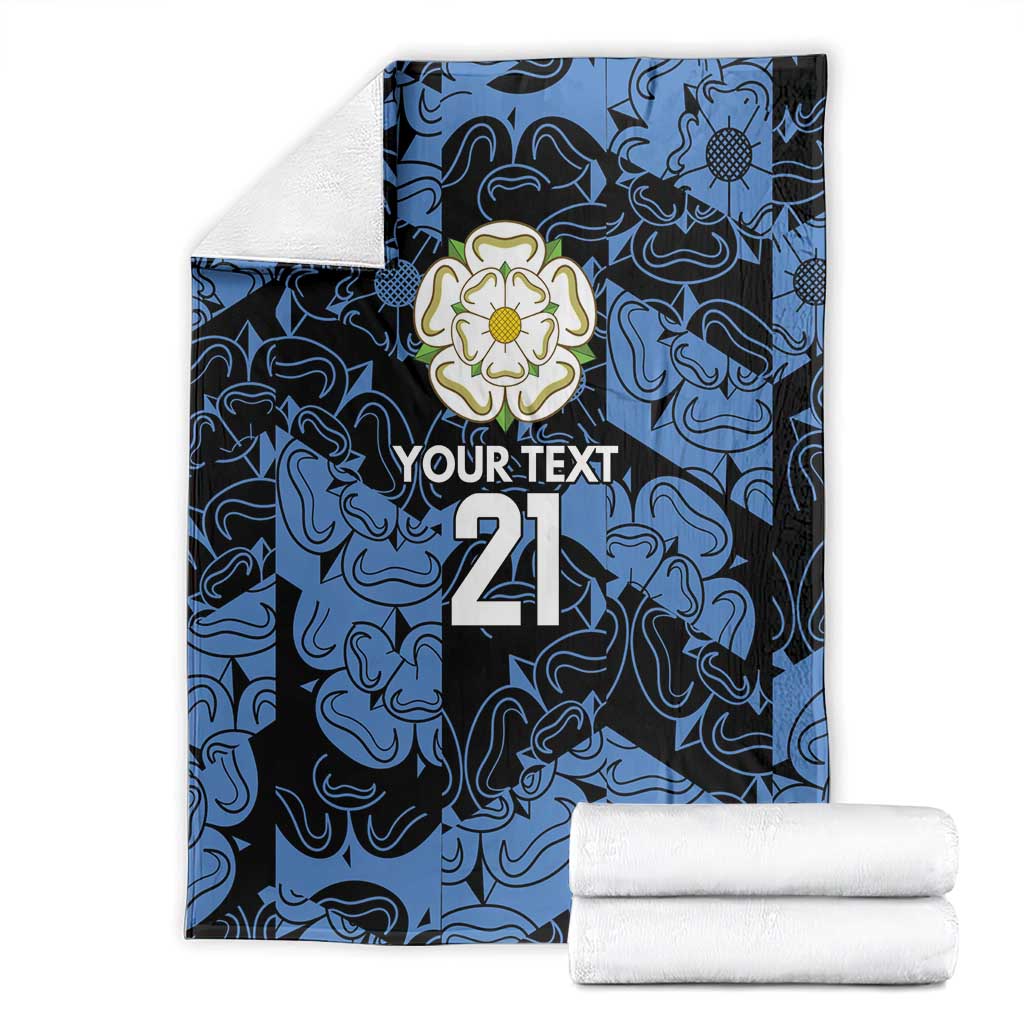 Personalized fleece blanket folded in blue and navy pattern with flower emblem, 'YOUR TEXT' and 21