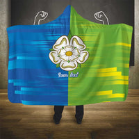 Green and blue hooded blanket with large white floral emblem and 'Your text'