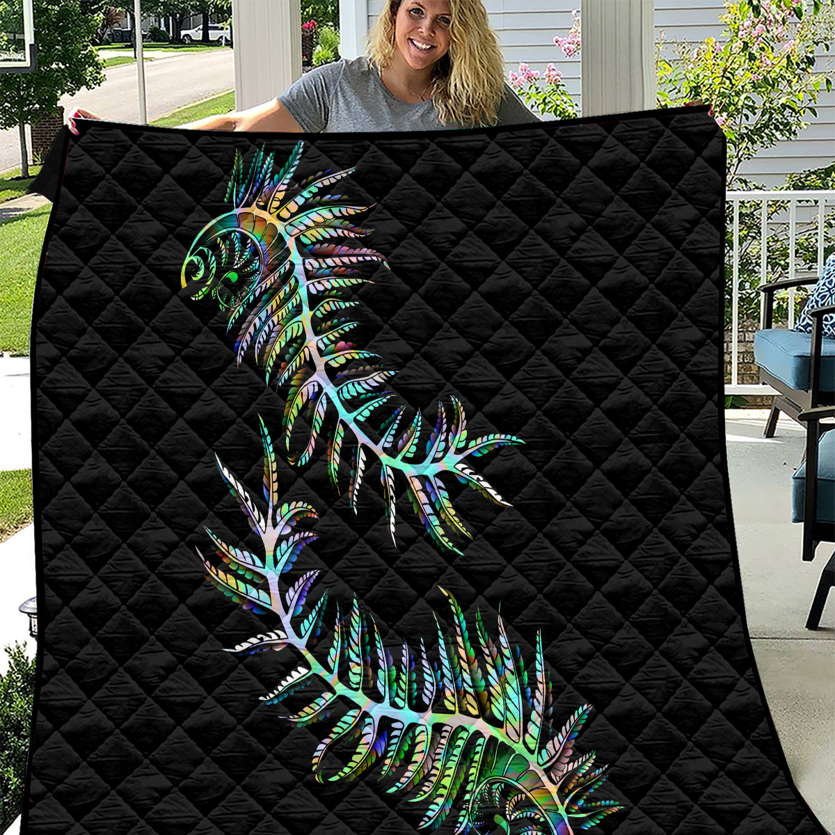 Black quilt with diamond stitching and colorful green-blue fern print, laid flat