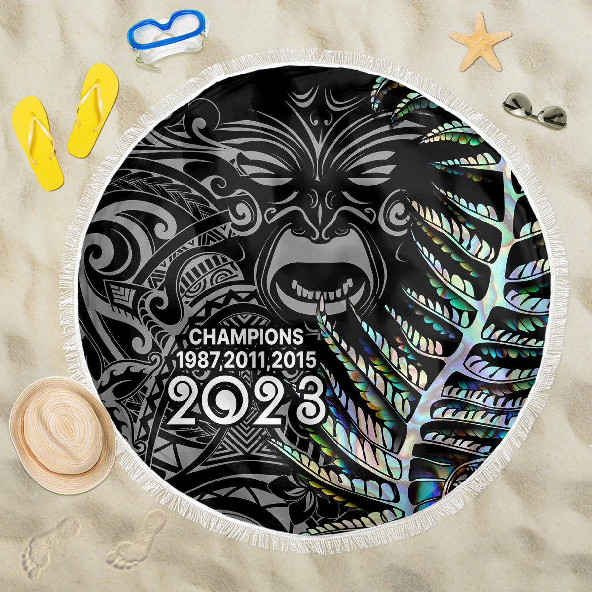 Black circular beach blanket with white fringe and Maori-style 2023 shark graphic