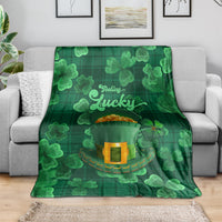 Green throw blanket draped over sofa with shamrock pattern and 'Feeling Lucky' print
