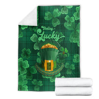 Folded green throw blanket set with shamrocks, 'Feeling Lucky' text, and hat graphic