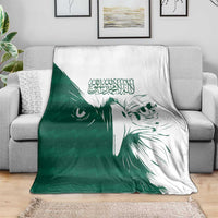 Green and white falcon pattern throw blanket folded over a gray couch back