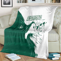 Green and white falcon pattern blanket on a sofa with matching books and rug
