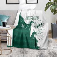 Green and white falcon pattern blanket draped on a gray sofa in living room