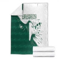 Green and white falcon pattern blanket with stacked white folded blankets