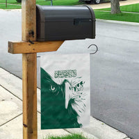 Green and white Saudi falcon garden flag on a wooden post with Arabic text
