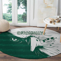 Green round carpet showing white falcon face and Arabic calligraphy motif