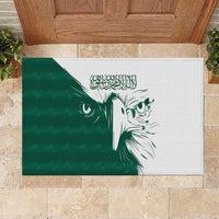 Green rubber doormat with white and dark-green falcon face graphic and Arabic text