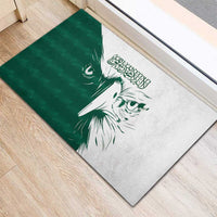 Green rubber doormat with diagonal white falcon face artwork and Arabic calligraphy