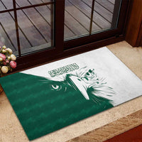 Green rubber doormat with wide falcon face graphic in white and Arabic text