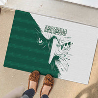 Green rubber doormat showing white falcon head artwork with Arabic calligraphy