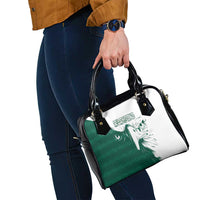 Green and white graphic handbag with black handles and adjustable shoulder strap