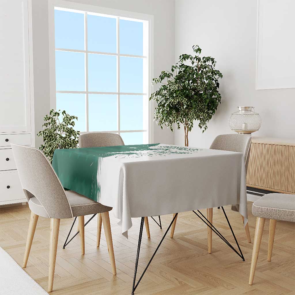 Green and white tablecloth with falcon motif and Arabic text, draped on dining table