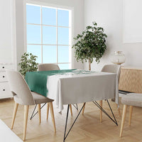 Green and white tablecloth with falcon motif and Arabic text, draped on dining table